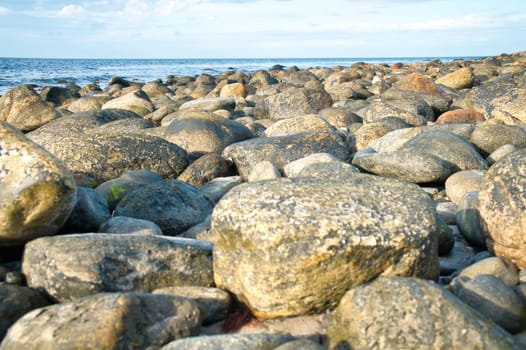 Big stones on stone beach in front of sea with clouds in sky. Denmark in Scandinavia. Landscape shot from nature in the north