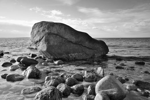 Large stone in black and white taken in the water on the beach in the sea. Danish coast on a sunny day. Landscape shot on the water