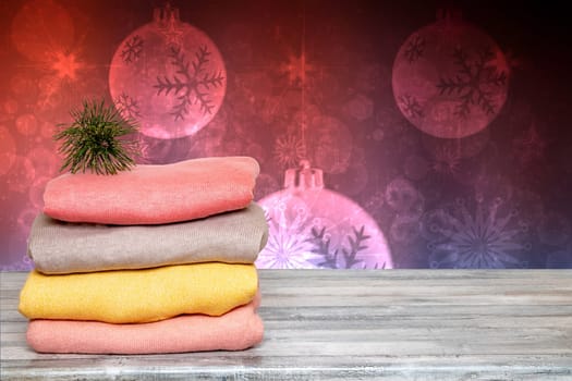 Template for christmas sale. Pile of colorful knitted cozy warm cashmere sweaters on a wooden table isolated against abstract xmas background.