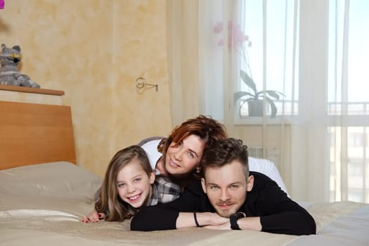 Happy family lie together in bed at home