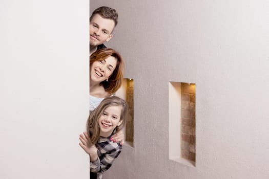 Tricky family peeks around the corner of the wall at home