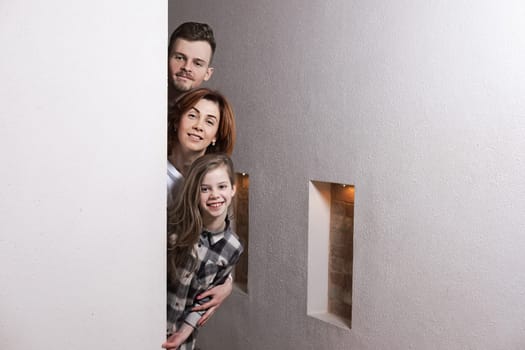 Tricky family peeks around the corner of the wall at home