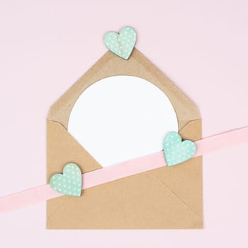 Valentine day greeting card, envelope with hearts on pastel background, love symbol, flat lay
