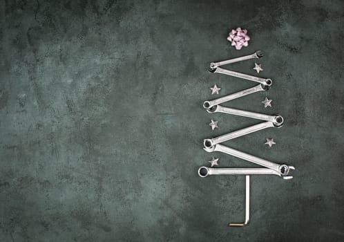 Christmas tree made with wrenches and stars, new year greeting card with repair tools, dark background