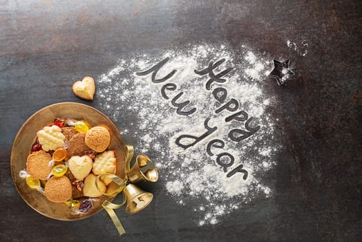Happy New Year written text made with flour with decorations objects and cookies. Holidays, celebration background. Christmas and New Year background