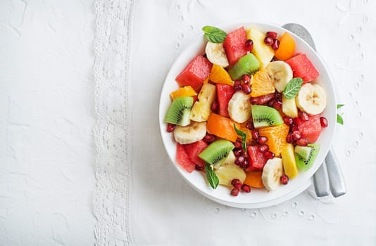 Bowl of healthy fresh tropical summer fruits on white background, top viewFresh salad bowl with tropical summer fruits
