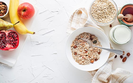 A bowl of dry granola and muesli served with fresh fruit, nuts and honey. Oatmeal plate. Healthy food, diet. Top view.