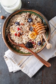 A bowl of dry granola and muesli served with fresh fruit nuts and honey. Oatmeal plate. Healthy food, diet. Top view.