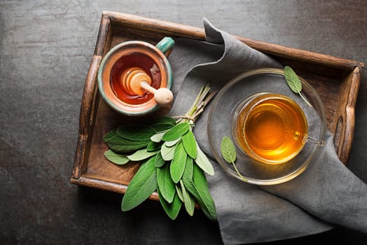 Sage tea in a cup with honey served on a trey close up