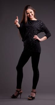 A long-haired beautiful self-confident woman posing in a classical thumbs up all right pose