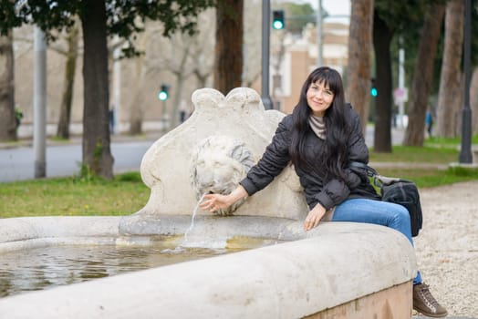 Tourist girl visiting the Lion Fountain, near the Santa Maria in Cosmedin in Rome (Italy)