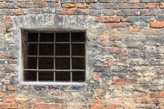 View of a detail of an ancient wall with grate