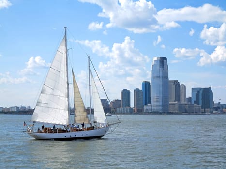 A sail boat on the water with a city behind
