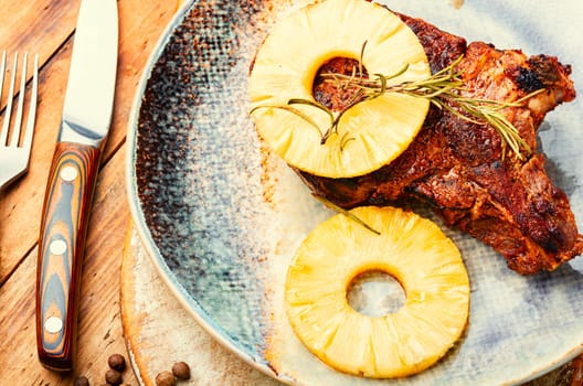 Tasty meat chop prepared with pineapple rings on old wooden table. Copy space