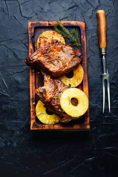 Tasty meat chop prepared with pineapple rings on old wooden table. Copy space