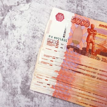 Russian cash banknotes worth five thousand rubles, the bundle lies on a gray background, there is a place for an inscription and text. Layout, mockup.