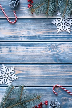 Vertical composition frame of Xmas decoration greeting card with empty wooden space. Cones, lollipops, candies and evergreen tree branches as border. Happy new year, merry christmas eve. Top view