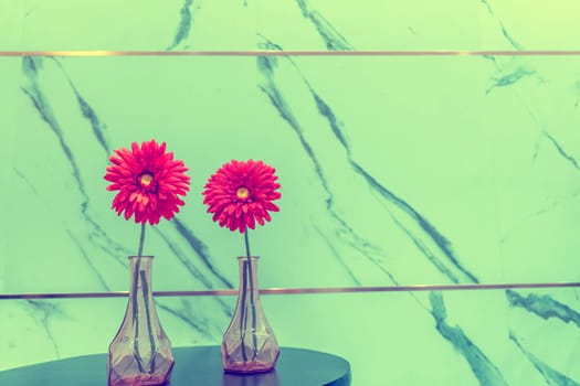 Red flowers in vase on marble wall background