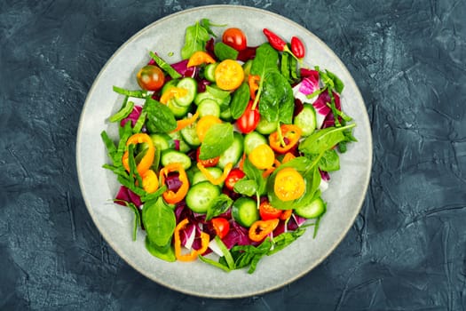 Summer delicious salad of tomatoes, cucumbers, peppers and spinach.