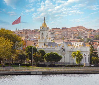 View from Golden Horn of Neo Byzantine architecture style Bulgarian St. Stephen Church, a Bulgarian Orthodox church in Balat district, Istanbul, Turkey, with Turkish flag in the far end