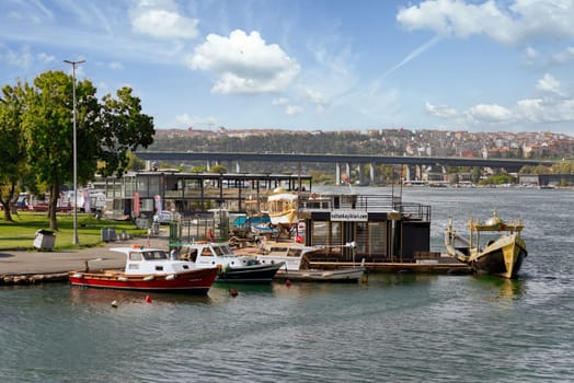 Small boat terminal by the coast of the Golden Horn, Istanbul, Turkey, in a sunny summer day, with Golden Horn Bridge in the far end
