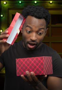 young man receiving a gift and opening box christmas night surprise holiday surprise decorated window
