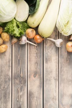 Vertical food composition of onion, cabbage, zucchini, squash marrow, garlic vegetables on wooden background. Grocery. Health care and farm produce. Balanced food flyer, Copy space, top view, flat lay