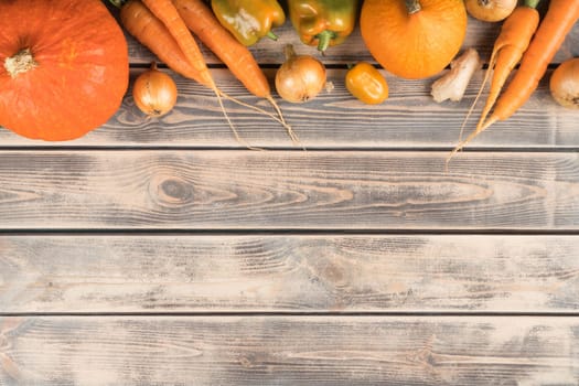 Orange food composition of assortment of healthy vegetables on wooden background. Pumpkin, carrot, onion, pepper. Grocery, food market. Balanced food for Halloween. Copy space, top view, flat lay