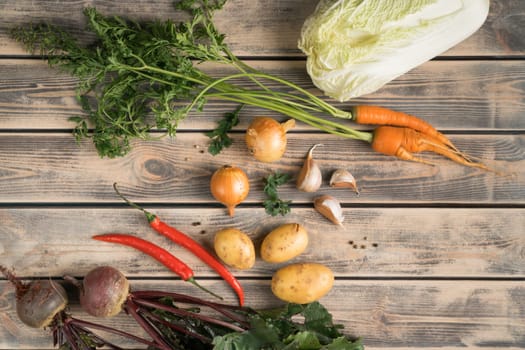 Vegetable food composition of onion, cabbage, beet root, chili pepper, carrot, potato and garlic on wooden table background. Healthy eating and cooking recipe. Top view, flat lay, copy space