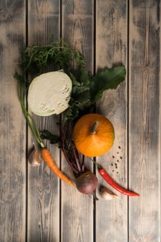 Vertical food composition of onion, cabbage, beet root, chili pepper, carrot, potato, garlic on wooden table background. Healthy eating and ecologic salad menu recipe. Top view, flat lay, copy space