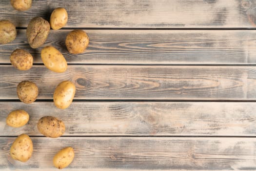 Composition raw potato on wooden background. Ecological foodstuff, farm products and healthy eating. Vegetarian lifestyle and natural agriculture. Cooking recipe with murphy. Top, copy space, sample