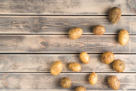 Organic farm potato bulbous on wooden background. Farm, raw food and healthy eating. Tasty and delicious products for market or store. Autumn harvest, seasonal food. Top view, copy space, flat lay