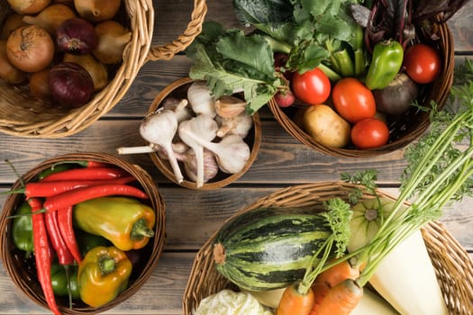 Abundance of food bowls on wooden table. Onion, garlic, bell pepper, chili, paprika, zucchini, carrot, cabbage, tomato and potato with greenery. Fast fresh food delivery and small business. Top view