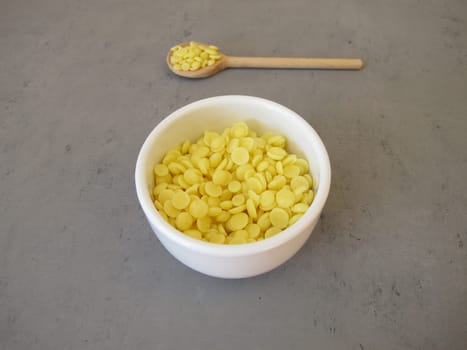 A bowl of light yellow cocoa butter chips as an ingredient for cooking and baking, chocolate making or personal care products