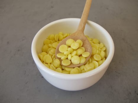 A bowl of light yellow cocoa butter chips as an ingredient for cooking and baking, chocolate making or personal care products