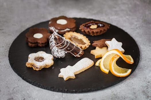 Tasty homemade Christmas cookies on black plate, closeup view