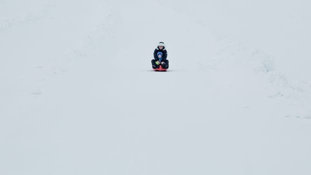 Mom and baby enjoy a sleigh ride. Sledding for children. Child riding a sleigh. Children play outdoors in the snow. Outdoor fun for family Christmas holidays.