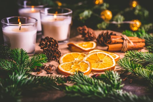 Dried orange and Christmas spices with branches of christmas tree, cinnamon, candles on kitchen table