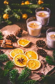 Dried orange and Christmas spices with branches of christmas tree, cinnamon, candles on kitchen table