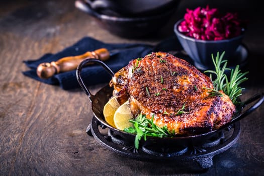 Roasted turkey knuckle with pickled red cabbage salad on wooden background