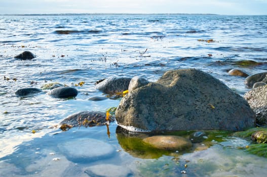 Large stone in the water on the beach in the sea. Danish coast on a sunny day. Landscape shot on the water