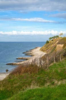 Hundested, Denmark on the cliff overlooking the sea. Baltic Sea coast, grassy meadow, beach. Clouds on horizon. Landscape photo from Scandinavia.
