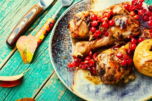Grilled spicy chicken legs baked with apples and berries. Fried chicken meat