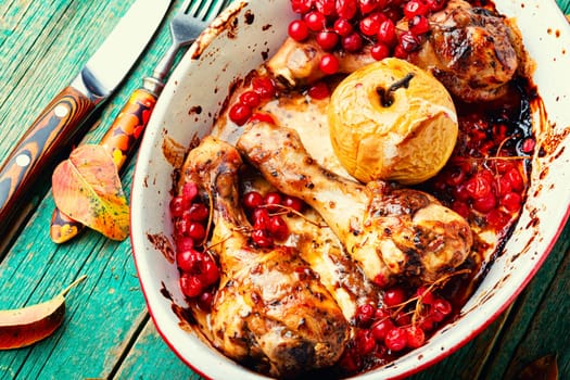 Grilled spicy chicken legs baked with apples and berries. Fried chicken meat