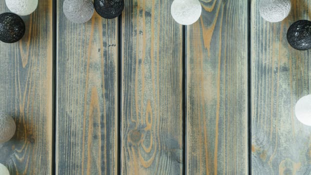 Light bulbs of garland of thread balls lying on old plank surface. Rustic holiday background, copy space. Merry Christmas and Happy New Year