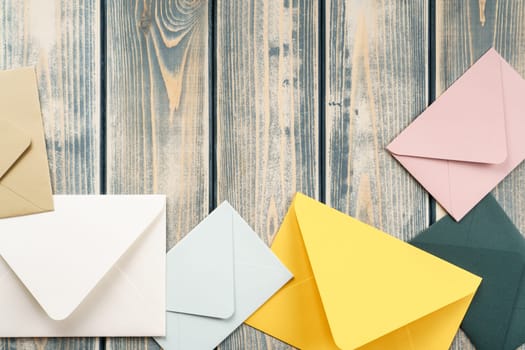 Multicolored envelopes lie randomly on gray wooden rustic textured background. Copy space. Place for text. Top view. Mail, correspondence, sending messages, congratulations