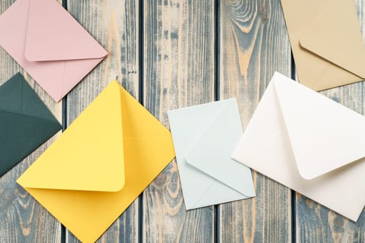 Multicolored envelopes lie randomly on gray wooden rustic textured background. Copy space. Place for text. Top view. Mail, correspondence, sending messages, congratulations