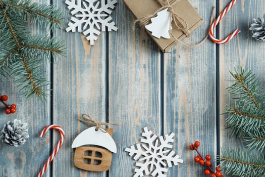 Frame Xmas greeting card with empty wooden space. Cones, lollipops, berries, snowflakes, present, toy house and evergreen tree branch as border. Happy new year, merry christmas