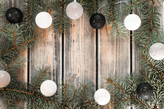 Light bulbs Christmas tree branches and balls garland frame on rustic gray plank surface. Holiday background, copy space. Merry Christmas and Happy New Year