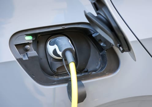 An electric car is charged at a charging station using a charging cable.